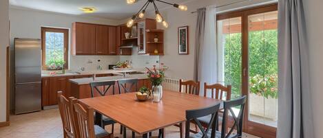 Une cuisine moderne avec des meubles en bois, un four encastré et un coin repas comprenant une table et des chaises en bois.