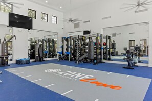 A spacious gym with weightlifting equipment, a large mirror, and a ceiling fan. - TWO Glendale CozySuites with Pool 2 & 9 (Glendale)