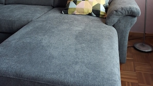 En grå sofa med en pude med geometrisk mønster, et billedværk på væggen og en gulvlampe.