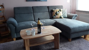 En stue med en modulsofa, et træbord, en vinflaske og to glas.