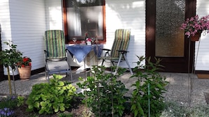 En overdækket veranda med et bord, stole og plantekrukker.