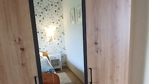Et værelse med en træskab, en seng, et lille bord og en væg med cirkulære mønstre.
