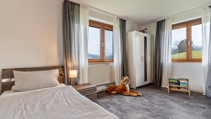 Un dormitorio con cama, un peluche de tigre, un radiador, un armario y una ventana con vistas.