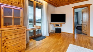 Un interior de madera con televisor, armarios de madera y vista a través de un ventanal.