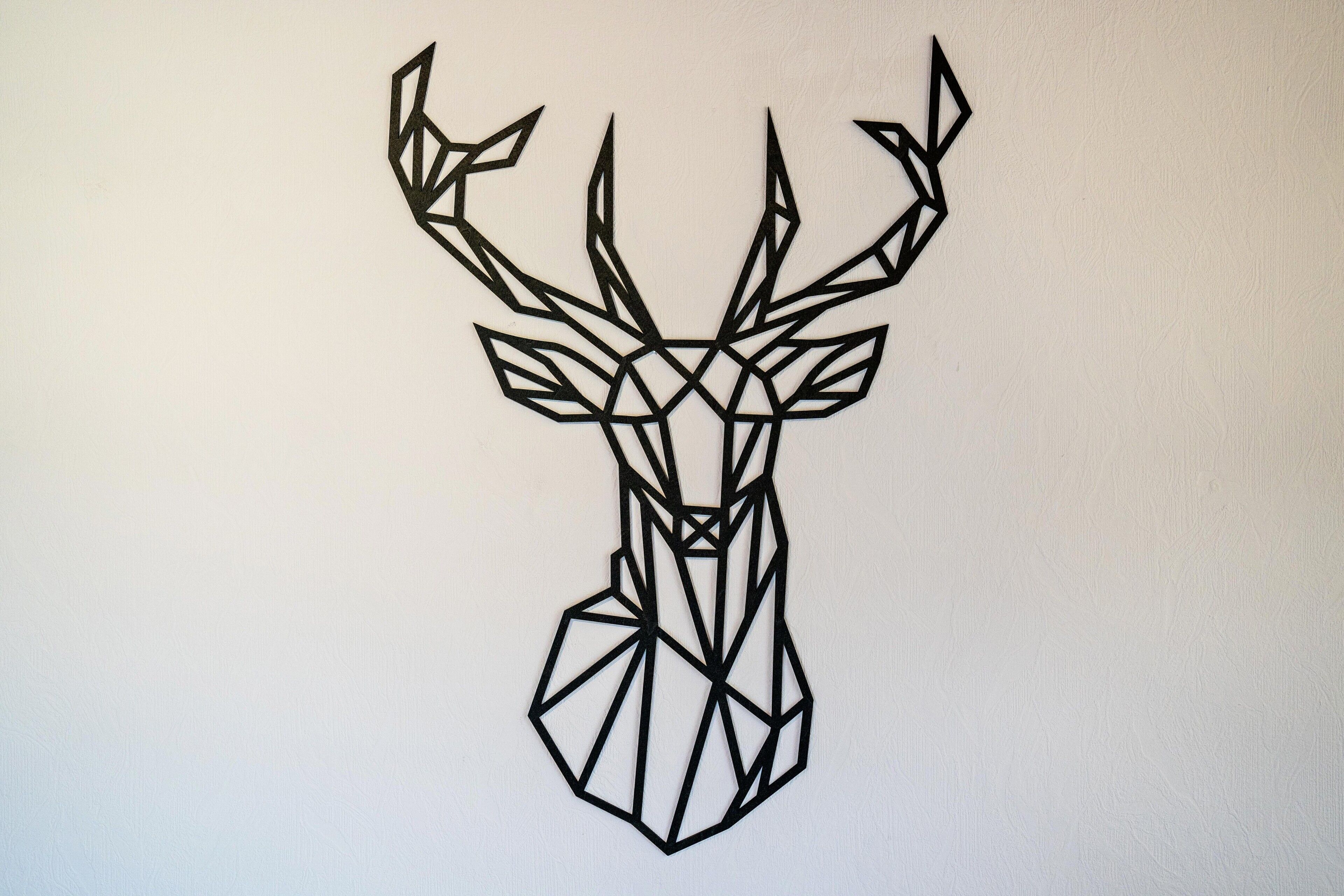 A geometric deer head design on a plain wall.
