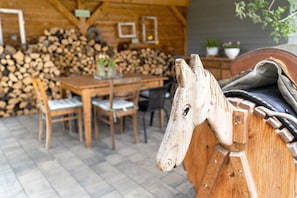 A wooden horse head sculpture, a wooden table with chairs, and a stack of firewood in a rustic setting. - Apartment 'Ferienwohnung Kleeblatt' with Wi-Fi (Herbolzheim)