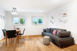A modern living room with a sofa, dining table, chairs, and a coffee table. - Apartment 'Ferienwohnung Kleeblatt' with Wi-Fi (Herbolzheim)