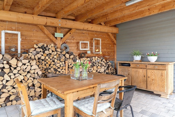 A wooden dining table with chairs, a wooden cabinet, and a stack of firewood. - Apartment 'Ferienwohnung Kleeblatt' with Wi-Fi (Herbolzheim)