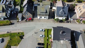 Oversigtsbillede af et boligområde med huse, en parkeringsplads og en vej.