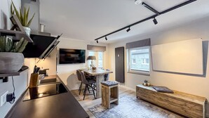 Una cocina moderna con comedor, televisor integrado y un amplio ventanal.