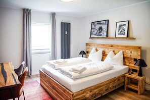 Un lit bien fait, avec du linge de lit blanc et des oreillers, une tête de lit en bois et deux tables de chevet avec des lampes.