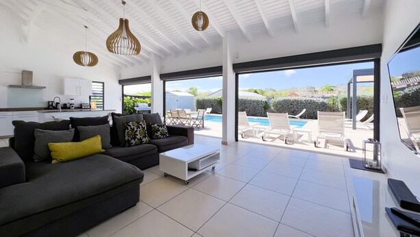 Un salon moderne avec un canapé, une table basse et une vue sur un espace piscine extérieur.
