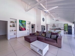 Una sala de estar moderna con un sofá modular, una mesa de centro blanca y una cocina al fondo.