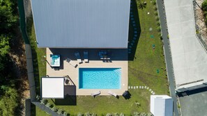 An aerial view of a building with a swimming pool, sun loungers, and a hot tub.