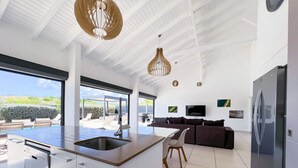 Une cuisine moderne dotée d’un grand îlot central, d’un coin repas et d’un espace de vie avec un téléviseur.