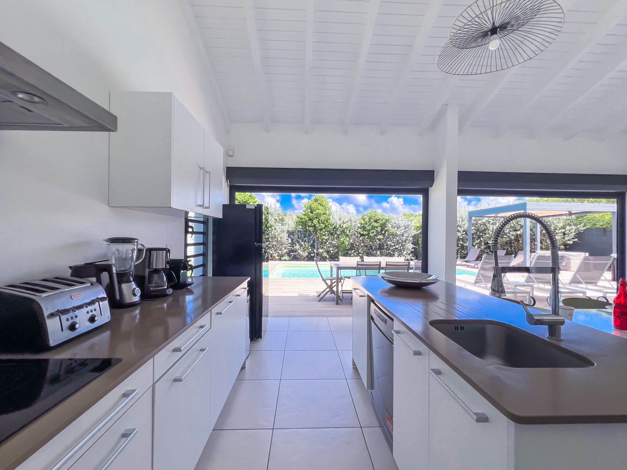 A modern kitchen with a view of a swimming pool and outdoor seating.