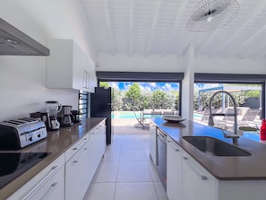 A modern kitchen with a view of a swimming pool and outdoor seating.