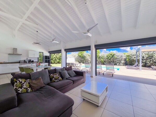 Una sala moderna con sofá, mesa de centro y vista a una piscina al aire libre.