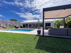 Un espace piscine comprenant des chaises longues, un jacuzzi et un coin salon abrité.