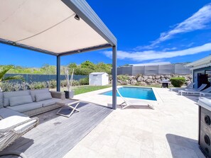 Un espace extérieur abrité comprenant une piscine, des chaises longues et un coin salon.