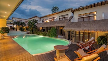 Una piscina al aire libre, sombrillas, sillones reclinables de piscina