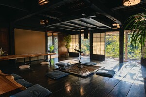 A traditional Japanese-style room with tatami flooring, a low table, cushions, and a small fire pit.