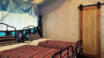 A room with a bed, a wooden door, and a window with sheer curtains.