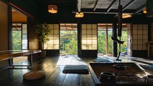 A traditional Japanese room with tatami flooring, a low table, a hanging kettle, and a view of greenery through large windows. - wood design park seto (Seto)