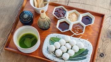 A wooden tray with a bowl of green tea, a bottle, and several small dishes containing different condiments.