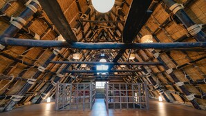 An attic room with a high, thatched ceiling and wooden beams. - wood design park seto (Seto)