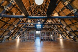 An attic room with a high, thatched ceiling and wooden beams.