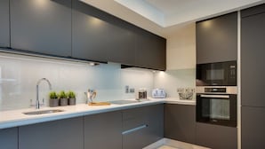 A modern kitchen with dark cabinetry, a stainless steel sink, a microwave, and an oven.