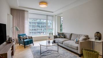 A modern living room with a sofa, armchair, coffee table, and a television.