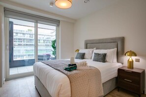 A bedroom with a bed, bedside table, and a view through a sliding door.