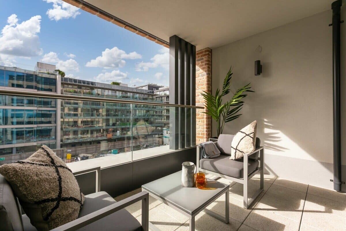 A balcony with a sofa, a small table, and a potted plant.