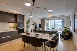A modern kitchen with a dining area, large windows, and a view of the city.