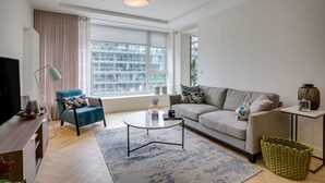 A modern living room with a sofa, armchair, coffee table, and a television. - The Benson Two by Dublin At Home (Dublin)