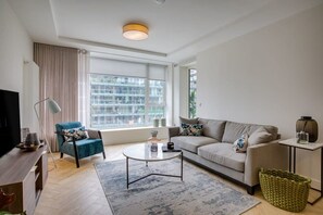 A modern living room with a sofa, armchair, coffee table, and a television. - The Benson Two by Dublin At Home (Dublin)