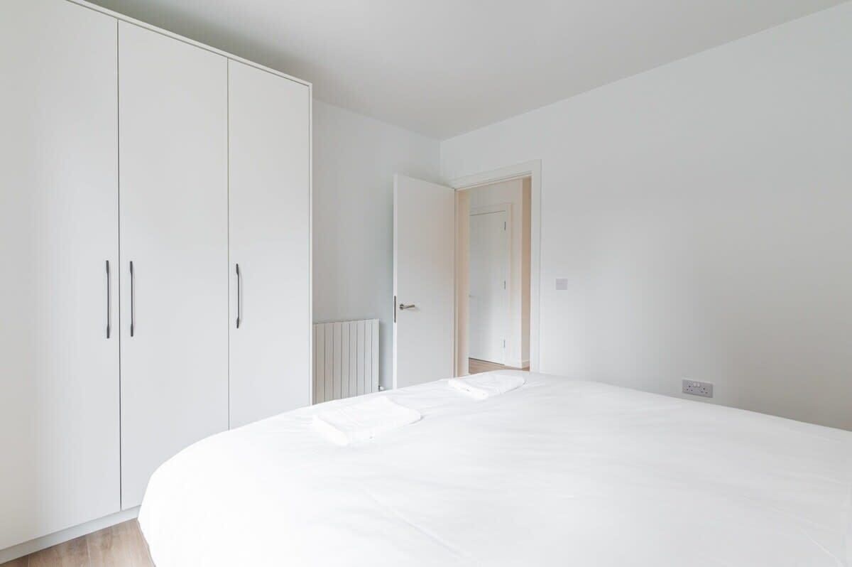 A bedroom with a large bed, a wardrobe, and a door leading to another room.