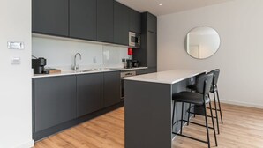 A modern kitchen with dark cabinets, a microwave, a coffee maker, and a round mirror on the wall. - Grange Two Summary:<br>T (Dublin)