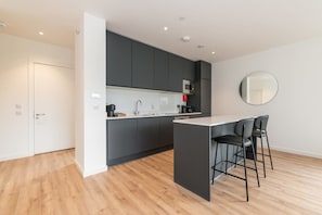 A modern kitchen with a central island, dark cabinets, and a white countertop.