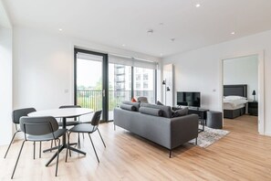 Un espace de vie moderne comprenant un canapé, une table à manger, des chaises, un téléviseur et un lit.