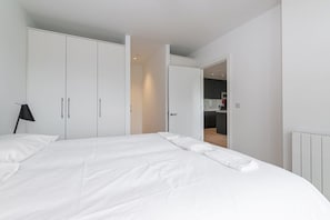 A bedroom with a large bed, white wardrobe, and a door leading to a kitchen area. - Grange Two Summary:<br>T (Dublin)