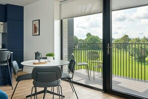 Un salon moderne avec une table ronde, des chaises, une machine à café et une plante en pot.
