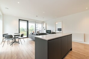 A modern kitchen with a central island, dining area with chairs, and a sofa.