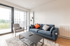 A modern living room with a grey sofa, a grey armchair, and a black coffee table.