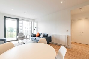 En moderne stue med sofa, lænestole, spisebord og en radiator.