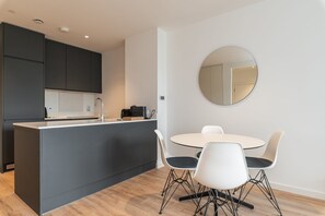 A modern kitchen with dark cabinets, a central island, and a round mirror on the wall.