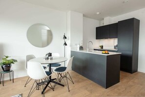 Una cucina moderna con isola centrale, un'area pranzo con tavolo e sedie rotonde, e un grande specchio a parete.