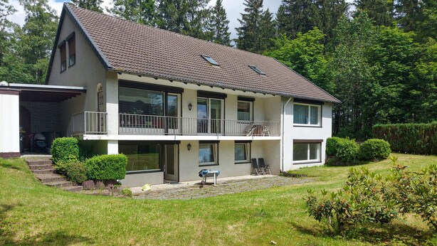 A two-story house with a balcony, a covered patio, and a well-maintained lawn. - Nice apartment in Goslar with WiFi (Goslar)